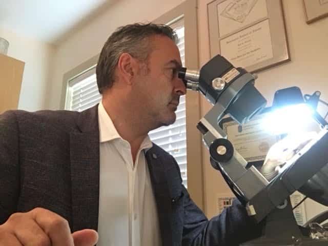 Ron G. Hanania, G.G. (GIA) appraising jewellery with a microscope